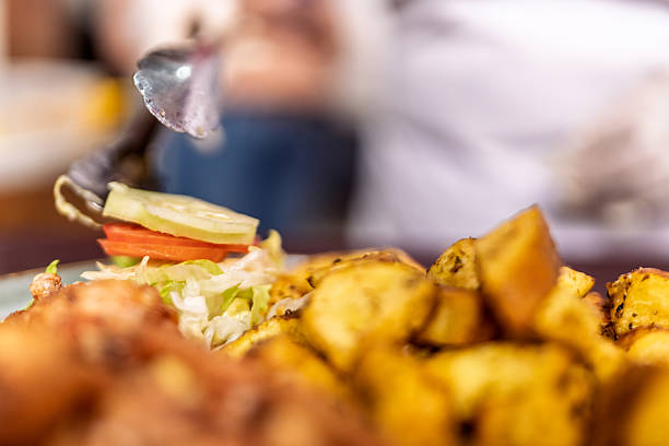 Chef using tongs plating fresh salad with cucumber, tomato, and lettuce next to golden fried potatoes