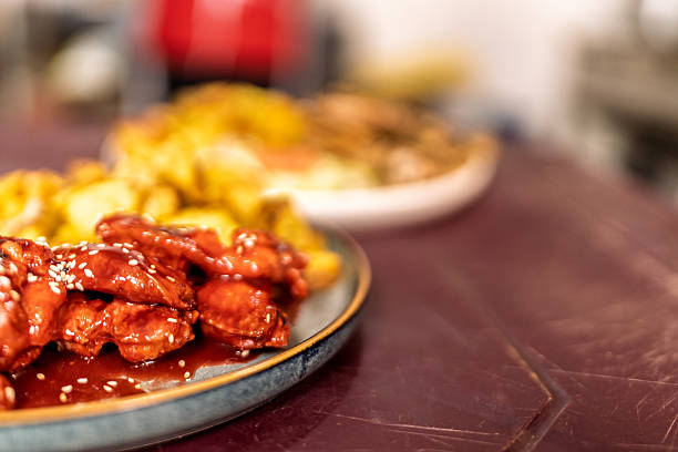 Crispy fried chicken wings coated in sweet chili sauce, topped with sesame seeds, presented on a plate