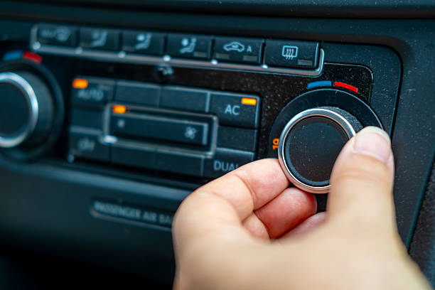 istock lose-up hand adjusting temperature dial car's climate control system, set 19C, with illuminated buttons for AC, AUTO, dual-zone settings, Climate comfort, User interface design, Automotive ergonomics 2238641417