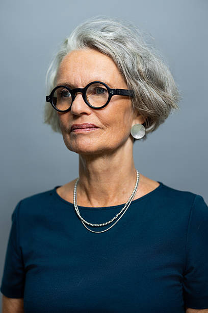 istock Senior woman looking away while standing against on grey background 2238643395