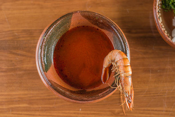 Thai soup Tom Yam from shrimp, chicken meat with mushrooms, tomatoes and lemon in a clay bowl isolated on a black background