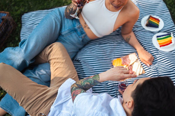 Lesbian Couple Relaxing Outdoors with Wine and Snacks on a Picnic Blanket
