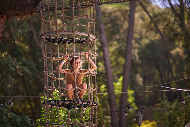 Boy smiling while playing on a rope net structure in an adventure park