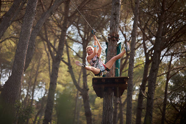 Woman smiling while ziplining through adventure park forest.