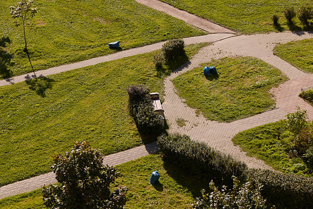 Captivating aerial view showcasing a vibrant and lush green park with charming winding paths and colorful waste bins