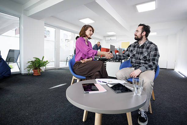 A busy Latin -American female talking to her new Caucasian ginger colleague in the office and they are getting along well with each other.