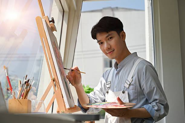 istock A Confident Asian painter works on his artwork in a sunlit studio, surrounded by tools and creative energy 2238666685
