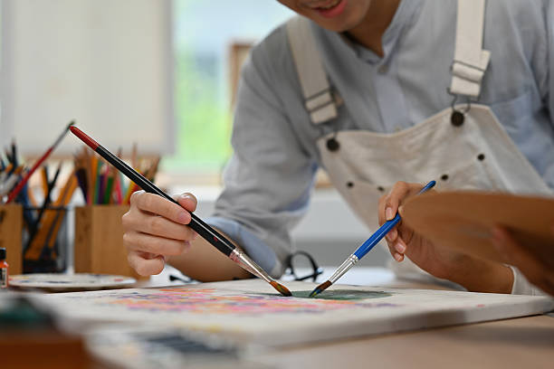 istock Close-up of two artists painting together on a shared canvas, blending creativity and teamwork in a studio 2238666783