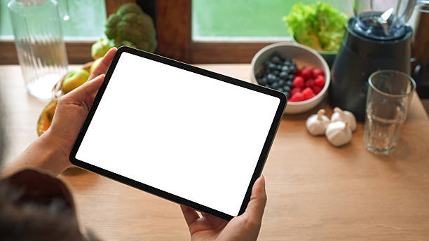 istock Hands holding digital tablet with blank screen in kitchen surrounded by healthy ingredients and blender 2238672695