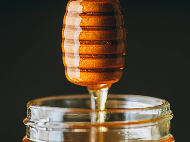 istock Honey dipper dripping with golden honey on dark background 2238673257