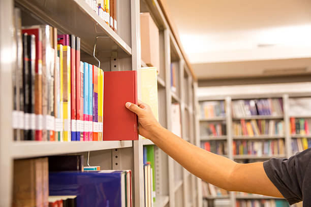 istock Close up hand picking a book from bookshelf in the library. Concepts for reading textbook and school for student knowledge education. 2238681077