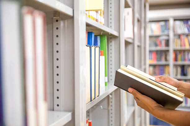 istock Close up hand picking a book from bookshelf in the library. Concepts for reading textbook and school for student knowledge education. 2238681078
