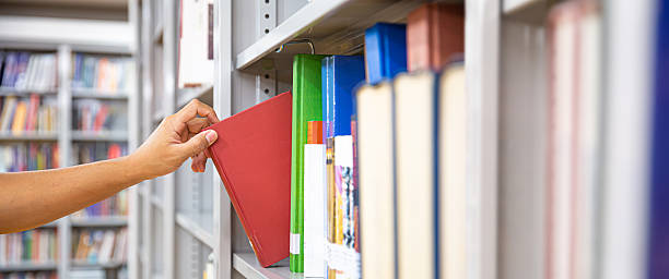 istock Book and library, Close up hand choosing and picking books from bookshelf in library. Concepts of reading textbook and school for student knowledge education or study and learning 2238682438