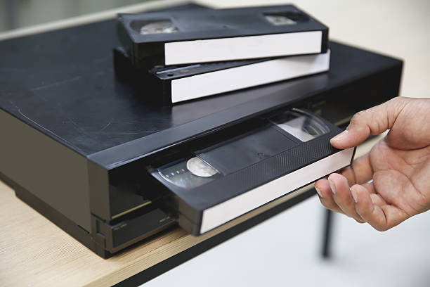 istock Close-up hand put or insert video cassette tape VHS old retro style on video record playback concept of vintage electric and electronic appliances multimedia player device old fashioned. 2238682472