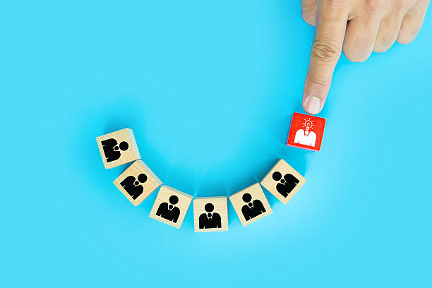 istock Hand choosing people head light bulb on cube wooden toy block stack. Concepts of ideas creative thinking or human resources personnel leader or leadership or business team player performance. 2238683623