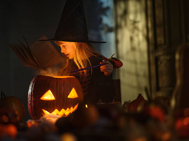 istock Cute little girl casting spells on Jack O' Lantern on Halloween. 2238685123