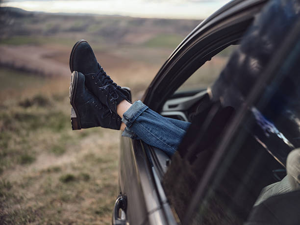 Unrecognizable woman's feet resting through the window car in nature. Photographed in medium format. Copy space.