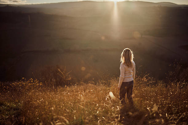 Rear view of a woman standing on a hill and looking at view in autumn day. Copy space.
