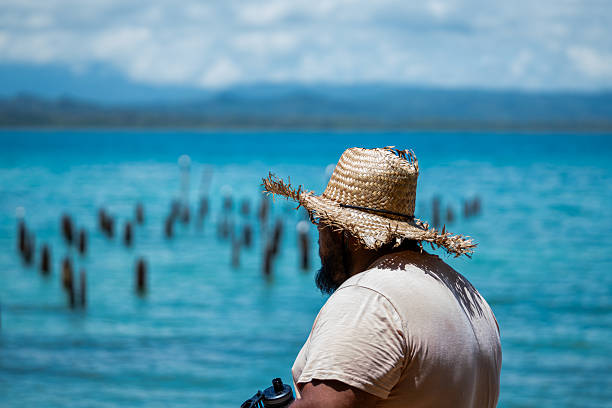 Local Costa Rican man enjoying his vacation wearing a straw hat on a Caribbean beach in Cahuita National Park, Costa Rica