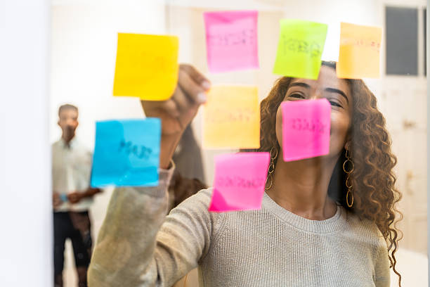 istock Happy woman brainstorming ideas on a glass wall with sticky notes 2238690159