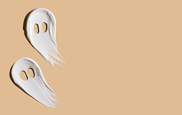 Halloween concept, ghosts in the form of cosmetic smears on a beige background. Creepy ghosts made of cream. Copy space. stock photo