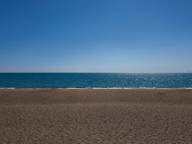 Beach sand background for summer vacation concept. Beach nature and summer seawater with sunlight light sandy beach Sparkling sea water contrast with the blue sky.