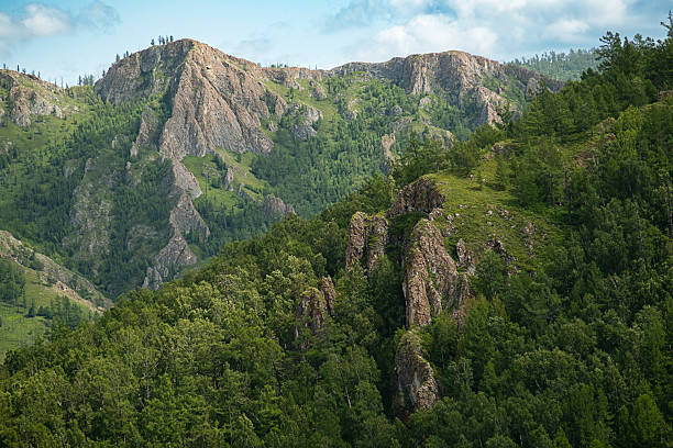 istock Vast green mountain range landscape with rugged rock formations and dense forest under blue sky. 2238709408
