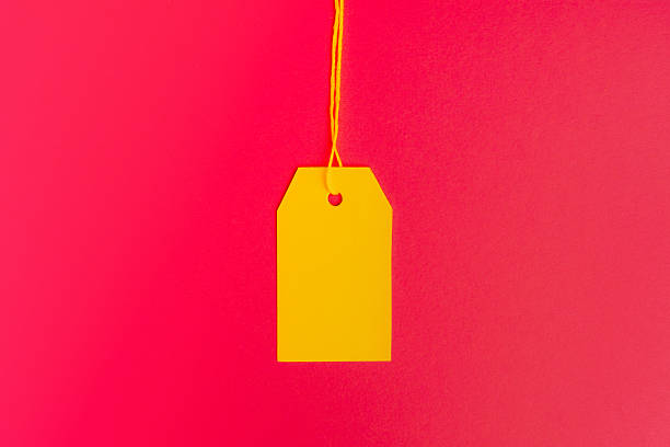 Centered yellow price tag on pink background with copy space. High quality photo