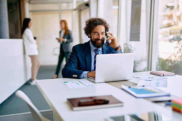 istock Business man working on laptop and talking on phone 2238714048
