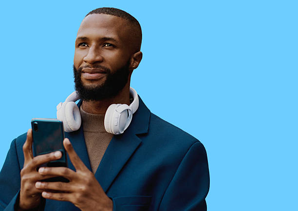 istock Confident Black Male Professional Wearing Headphones Using Smartphone On Blue Background 2238714536