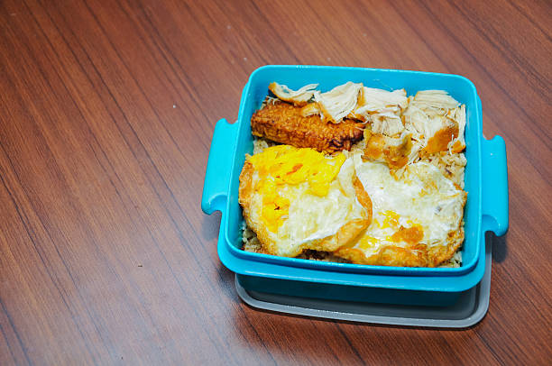istock a blue lunch box containing fried rice, eggs, and fried chicken is on the table 2238718600