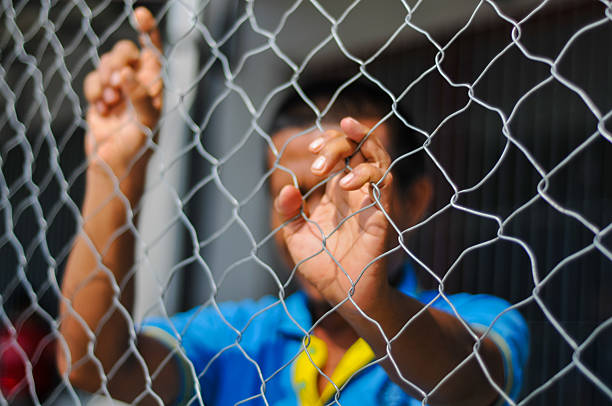 istock person's hands and face blurred behind the sharp focus of a chain-link 2238718672