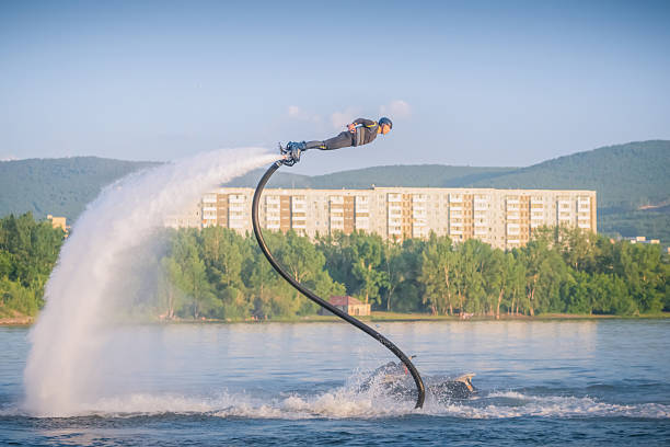Spectacular flyboarding display over calm waters with stunning backdrop during daylight hours. The flightboard athlete flies over the water like a superhero. acrobatics on a flyboard