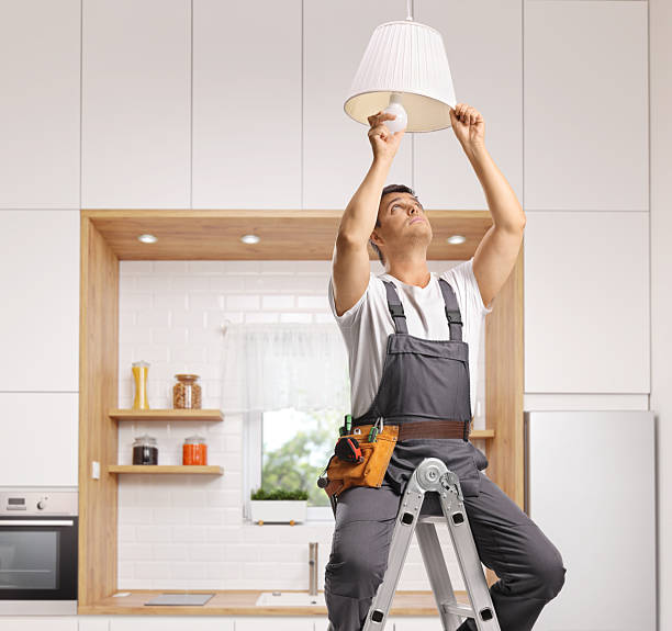 istock Repairman on a ladder changing a light bulb 2238722028