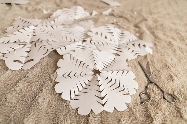 istock Paper snowflakes are carefully cut and scattered across a soft surface. Scissors rest beside the delicate designs, highlighting a creative winter activity perfect for festive decorations 2238722363