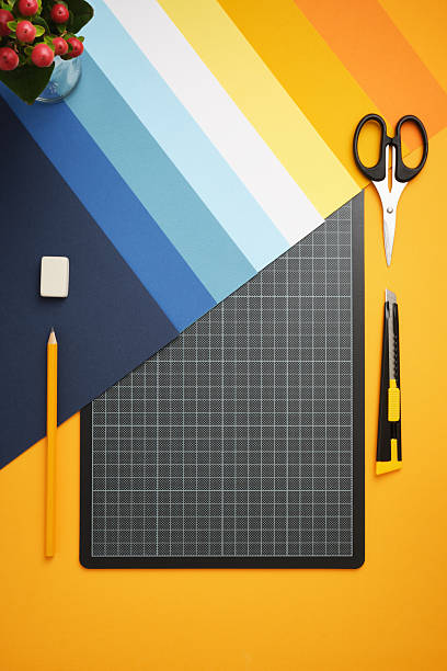 istock Workspace for DIY projects. Colored paper, cutting mat, pencil, knife, scissors, and eraser on a yellow background. Copyspace 2238727845