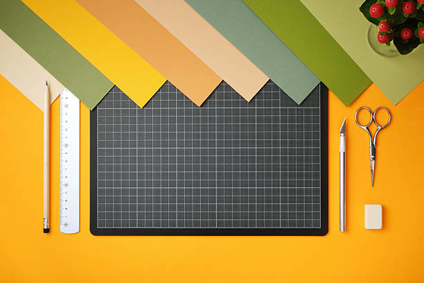 istock Workplace for paper art projects. Colored paper, cutting mat, pencil, knife, scissors, and eraser on a yellow background. Copyspace 2238727849