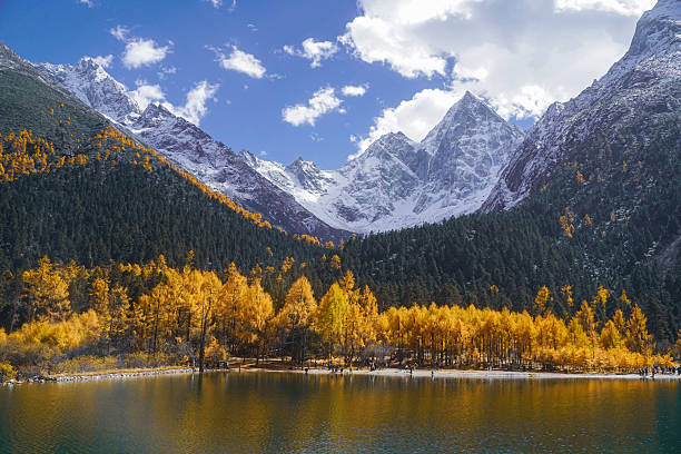 istock Snowy mountain peak with autumn forest and lake under blue sky with clouds 2238731054