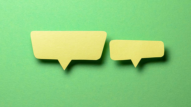istock Yellow blank cut out paper speech bubbles with copy space for text on green background, flat lay top view discussion conversation concept 2238735516
