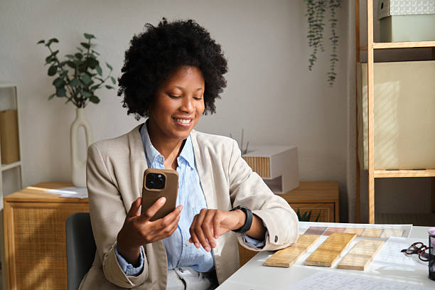 istock Female architect smiling, using smartphone and smartwatch in office 2238740473