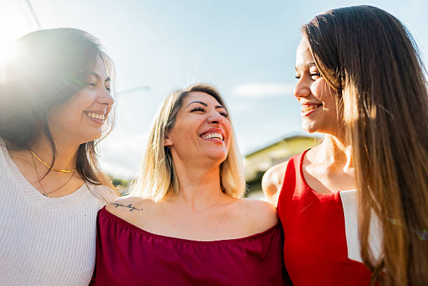 cheerful females middle age young womens friends together sitting on a sofa at home in leisure activity indoor. smile and enjoy the day hugging and touching with care and friendship