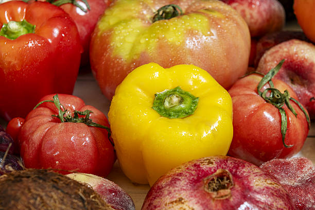 Still life with yellow peppers, ripe tomatoes and some fruit