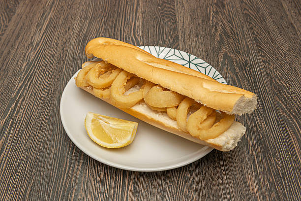 istock Fried calamari sandwich with lace tips, presented on ciabatta bread with fresh lettuce and spicy brava sauce. 2238747019