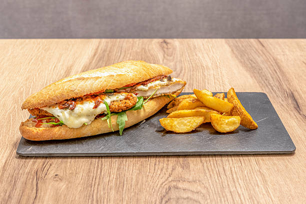 istock Fried breaded chicken sandwich with melted Parmesan cheese with tomato, arugula and fried potato garnish 2238747617