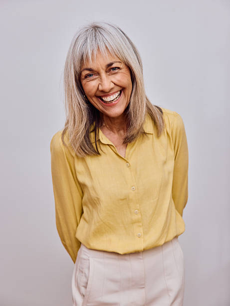 istock Cheerful senior woman laughing and leaning forward while standing against a grey background 2238751074