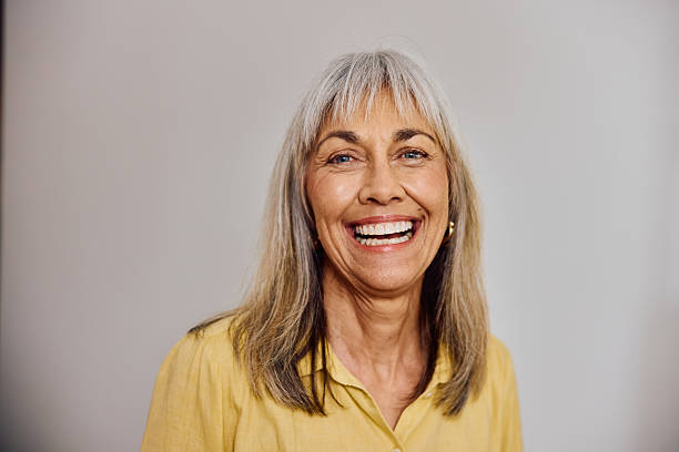 istock Joyful grey-haired woman laughing and looking at camera while standing in front of a neutral background 2238751128