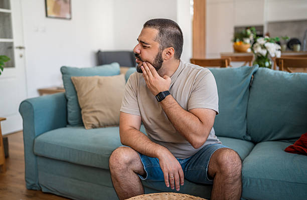 istock Man suffering from toothache sitting on couch at home 2238751758