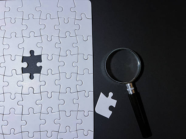 istock Missing puzzle piece with magnifying glass on black background 2238754181