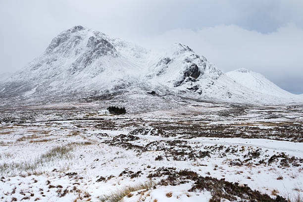 Winter wonderland view of Lagangarbh Cottage and snow covered mountains in Glencoe, Scottish Highlands, UK.