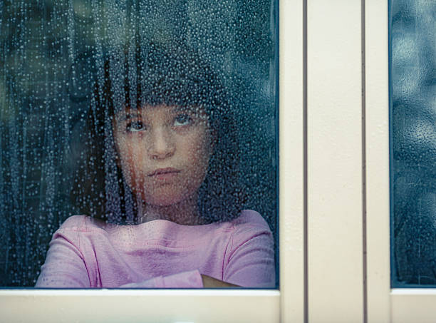 istock Young girl looking out rainy window feeling bored 2238757368